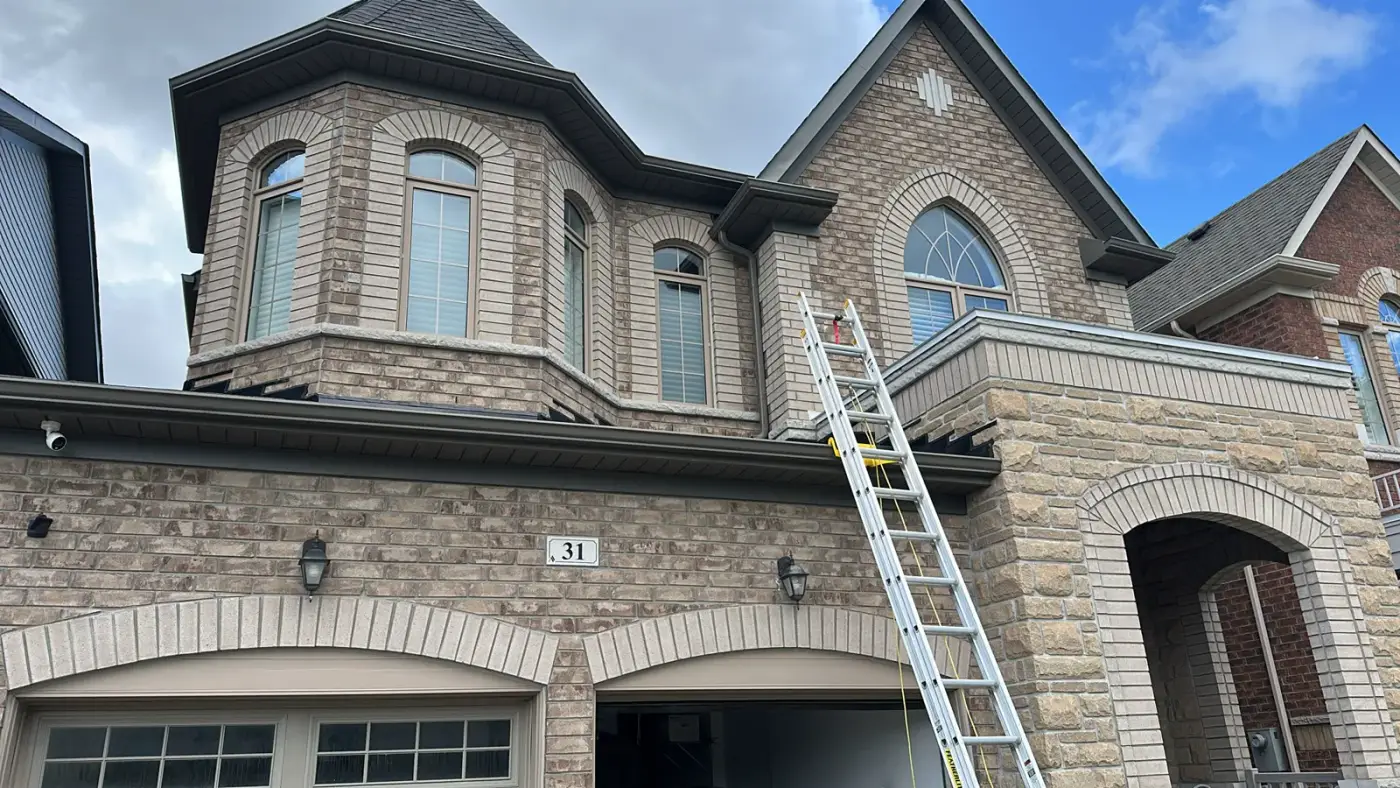Toronto Glow installer on a ladder against a brick home preparing to install permanent lighting track