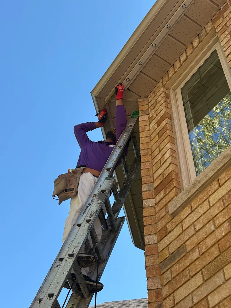 Toronto Glow installer on a ladder mounting permanent lighting track under a soffit