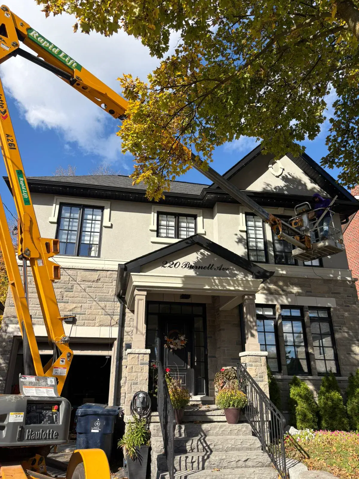 Toronto Glow installer using a bucket lift to install permanent lighting on a large home