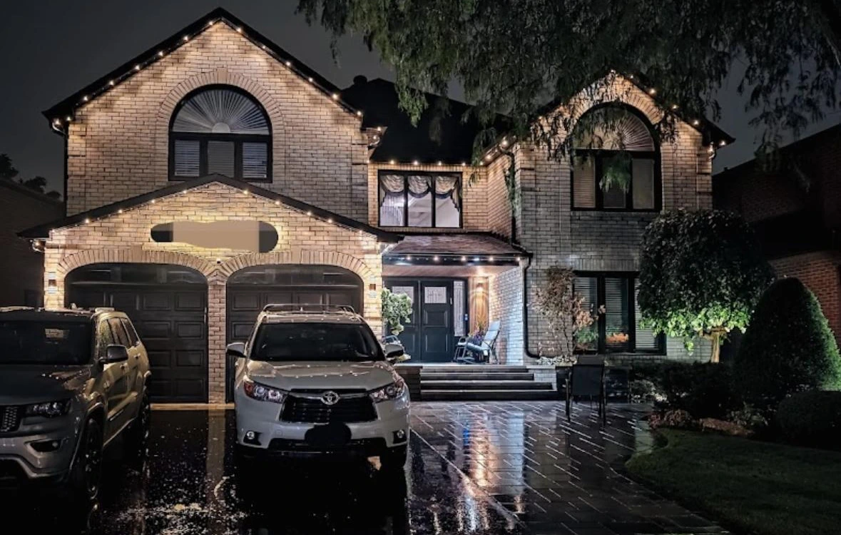 Two-storey brick home with permanent lights following its front-facing roof peaks and garage roofline