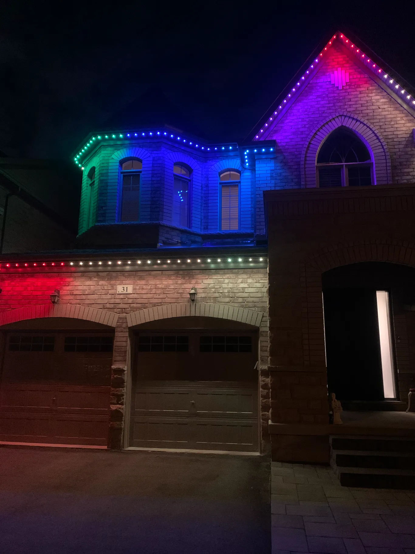 GTA brick home with rainbow permanent LED roofline lighting at night