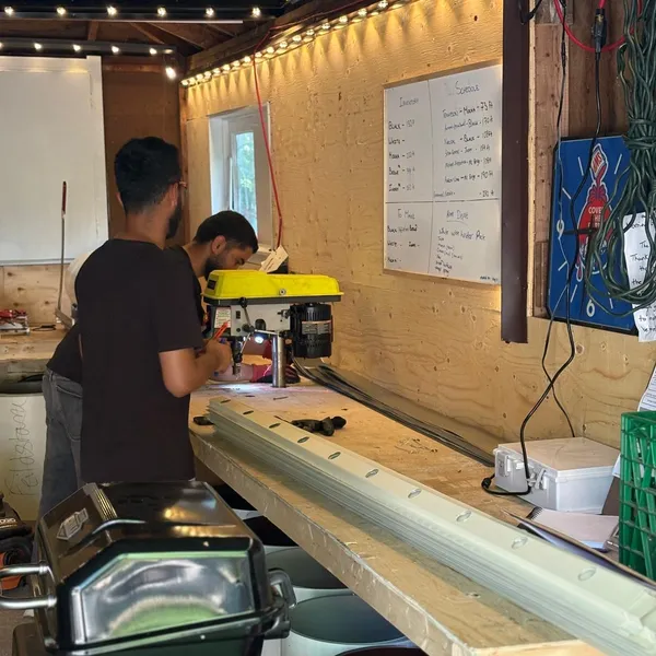 Toronto Glow team punching mounting holes into aluminum tracks at the North York fabrication shop