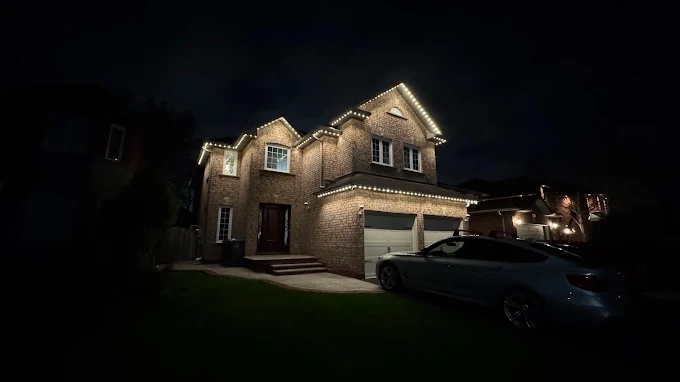 Large GTA home fully outlined with warm white permanent Christmas lights by Toronto Glow — roofline, soffit, and garage all illuminated against a dark night sky.