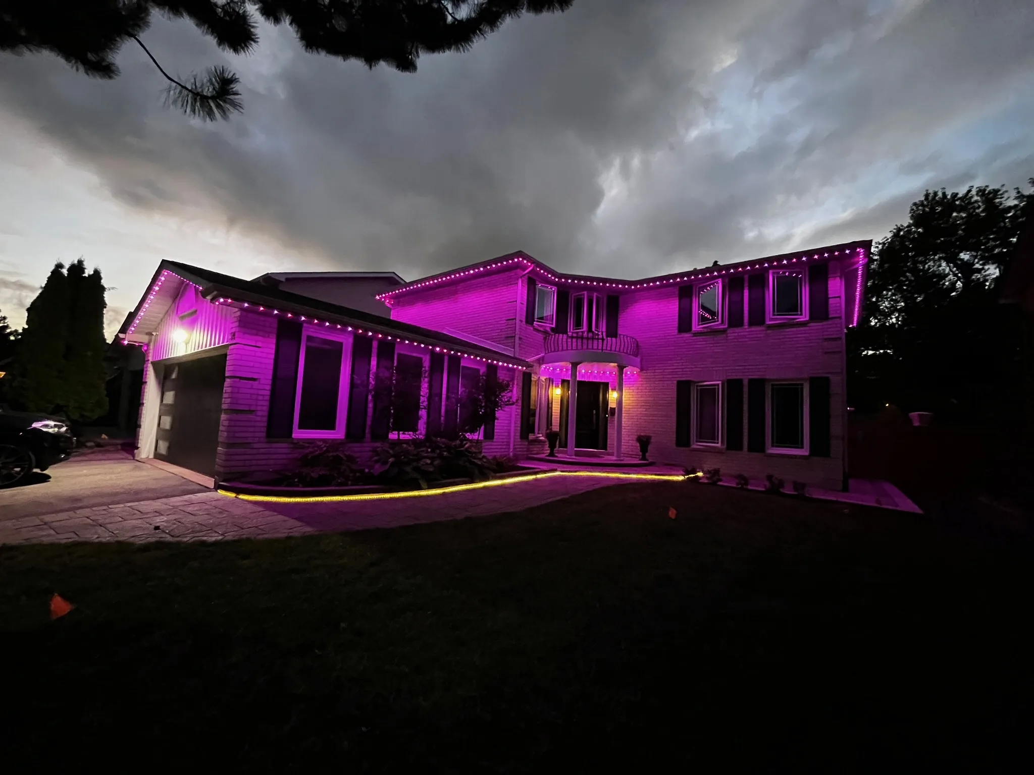 GTA home fully lit in vibrant pink and magenta permanent Christmas lights by Toronto Glow, glowing brilliantly against a dramatic evening sky.